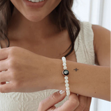 model wearing lunar gleam bracelet in gold on wrist with white shell beads